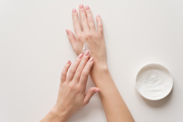 Foto a menina distribui creme hidratante nas mãos.