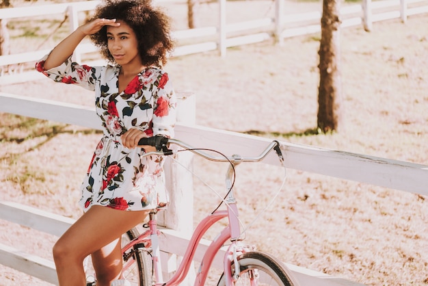 A menina do mulato está ao lado da trilha de raça com bicicleta.