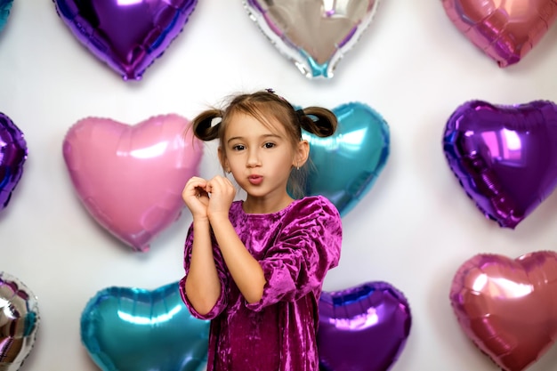 A menina dobrou as mãos em forma de coração e beijou.