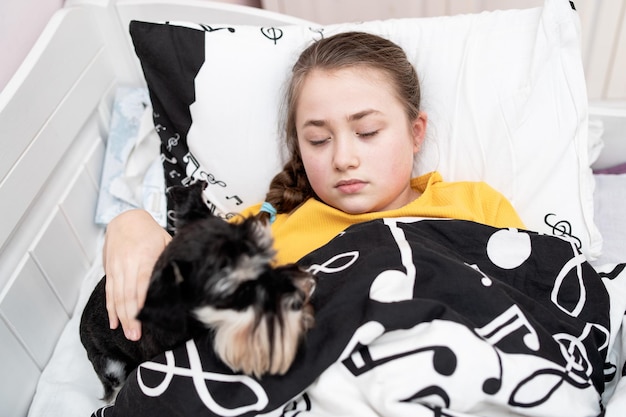 A menina doente está descansando ao lado de seu cachorro na cama