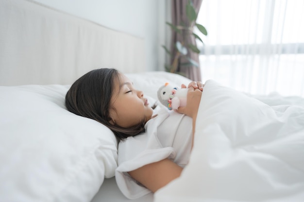 A menina dorme em um confortável quarto branco