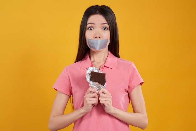 A menina é não pode comer o chocolate isolado no amarelo.