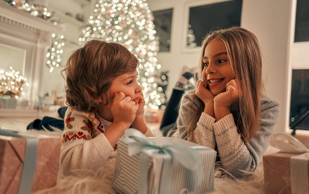 A menina e o menino felizes com presentes no chão