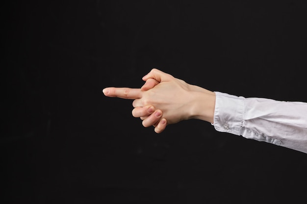 A menina em uma camisa branca dispara de uma pistola abstrata da mão em um espaço preto.