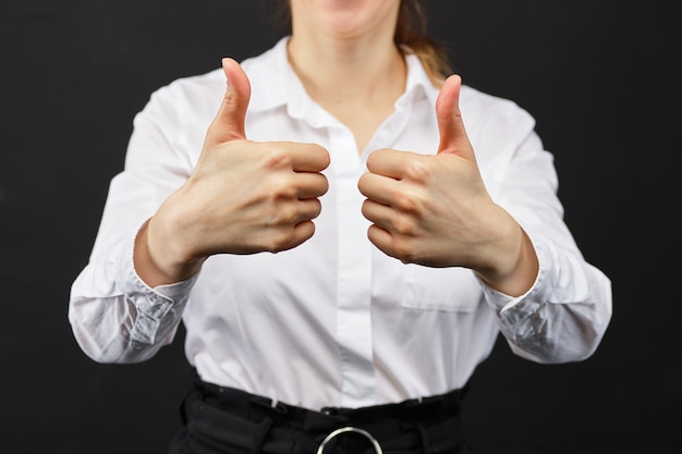 A menina em uma camisa branca manuseia acima das mostras em um fundo preto.