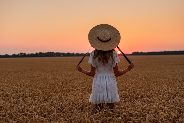 Foto a menina encontra o amanhecer em um campo de trigo ela toca as espigas e caminha pelo campo