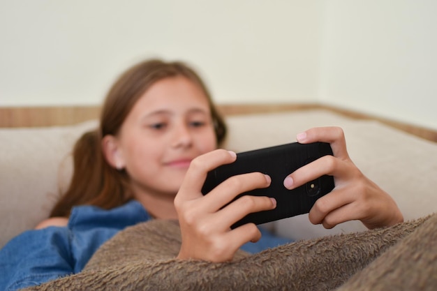 A menina encontra-se no sofá com o telefone. menina adolescente