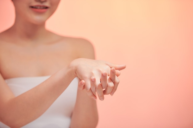 A menina esfrega as mãos com um creme cosmético que deixa a juventude e a elasticidade da pele