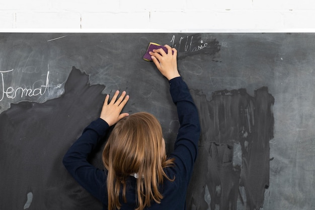 Foto a menina esfrega os quadros da escola com uma esponja o aluno de serviço prepara um lugar no quadro da escola