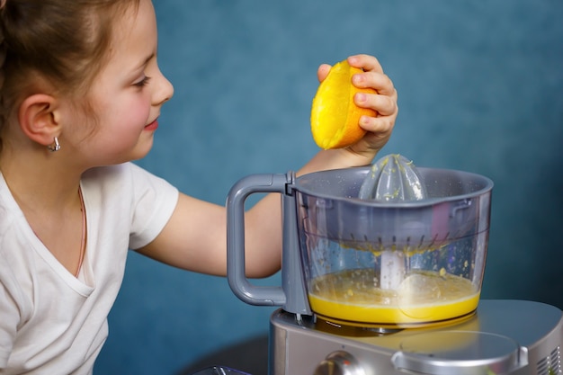 A menina espremeu suco fresco de frutas de maçãs e laranja. vitaminas e alimentação saudável para crianças.