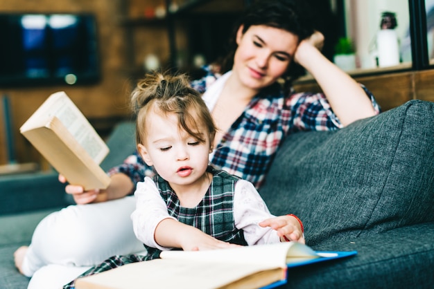 A menina está aprendendo a ler um livro com a mãe