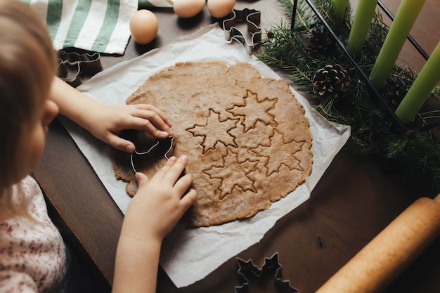 A menina está assando biscoitos de gengibre de Natal.