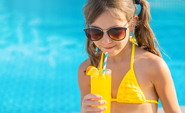 A menina está bebendo um coquetel na piscina