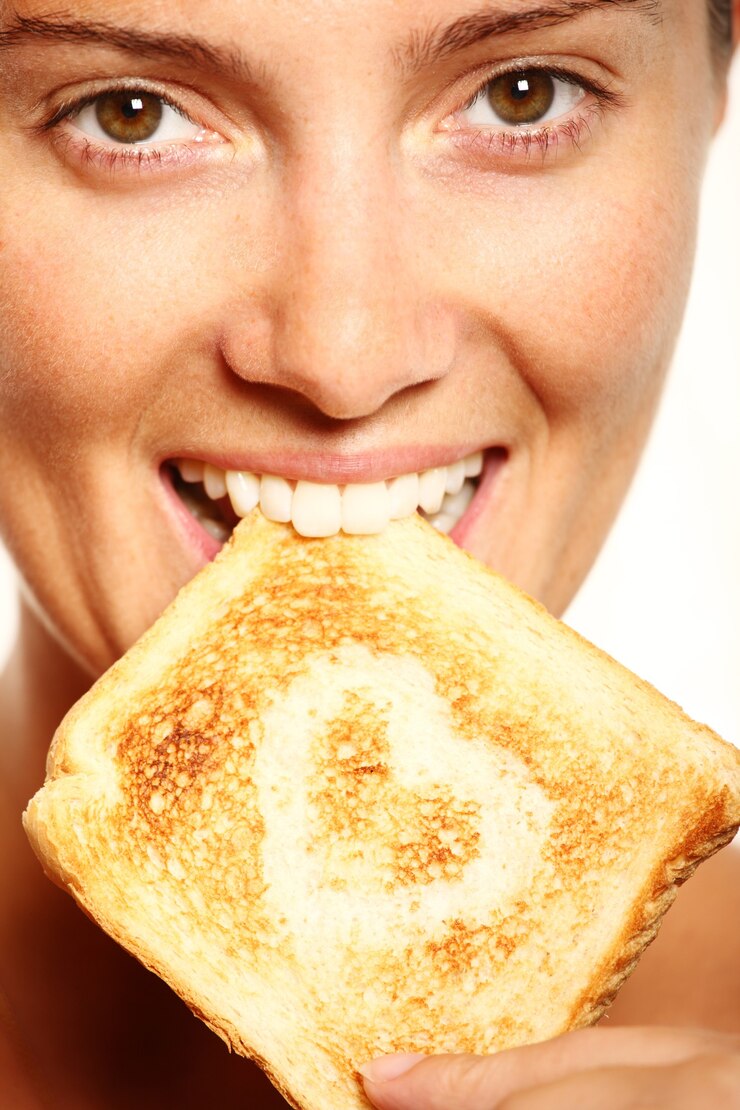 Foto a menina está comendo torrada fresca com formato de coração