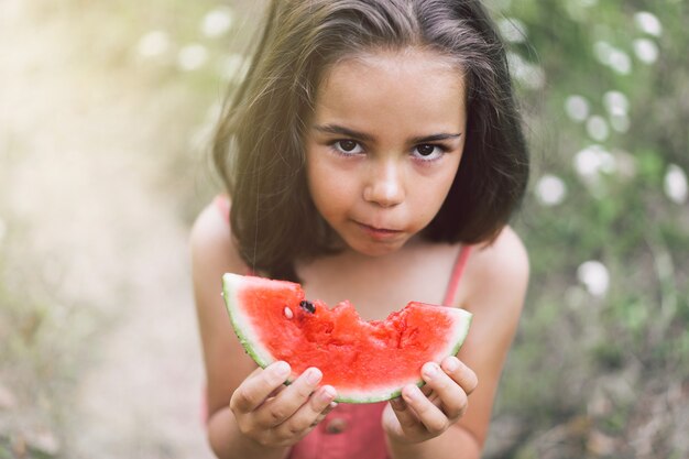 A menina está comendo uma melancia. Clima de verão.