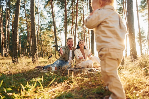 A menina está correndo Família feliz do pai mãe e filha está na floresta