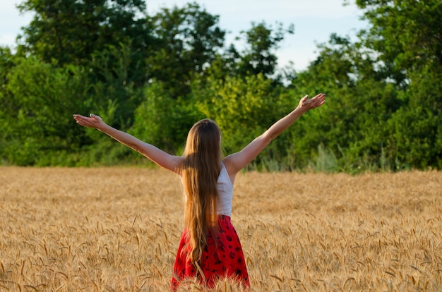 A menina está de volta a um campo de trigo com os braços erguidos para o céu