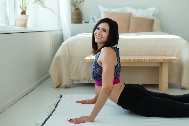 A menina está envolvida em ginástica, ioga, em sua casa.