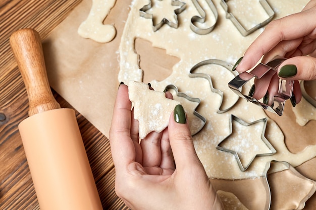 A menina está fazendo biscoitos de Natal de gengibre usando um formulário para cozinhar