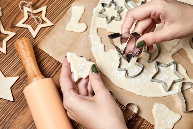 A menina está fazendo biscoitos de Natal de gengibre usando um formulário para cozinhar