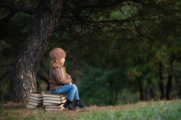 A menina está lendo um livro na educação infantil do parque