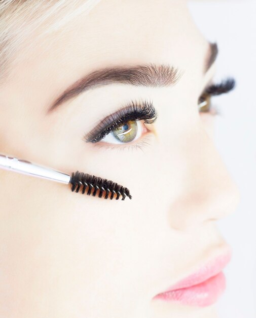 A menina está passando por um procedimento de extensão de cílios. Lindo close-up dos olhos, cílios grossos e pretos. O conceito de cílios artificiais, uma tendência.