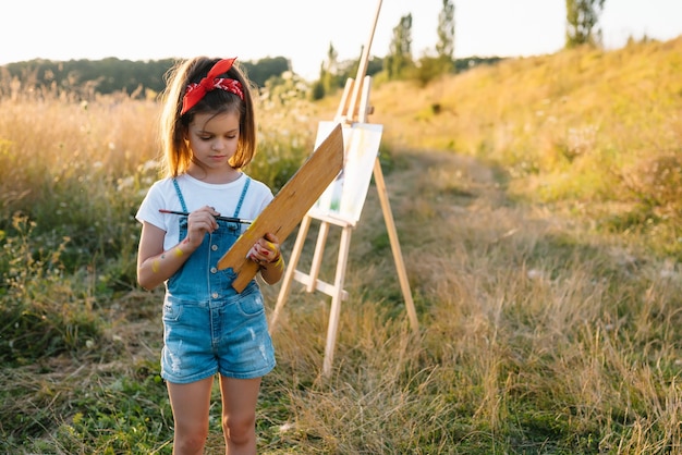 A menina está pintando uma foto ao ar livre