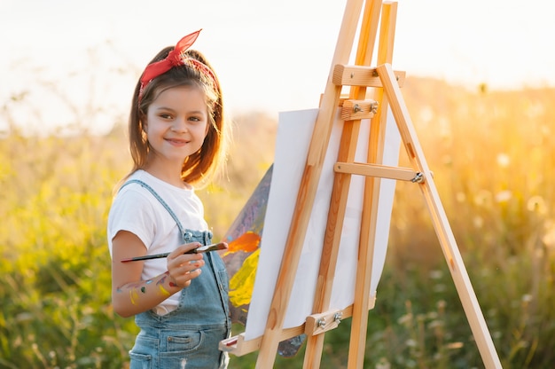 A menina está pintando uma foto ao ar livre