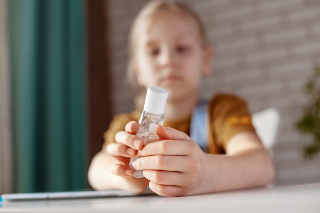 A menina está segurando um gel anti-séptico. Prevenção, desinfecção das mãos, prevenção de infecção. O conceito de um estilo de vida saudável