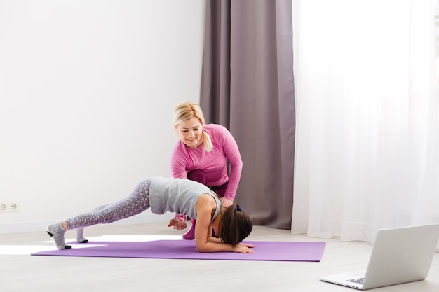 A menina faz ginástica em casa. vídeo tutorial de ginástica. exercícios de ginástica. a ideia de uma atividade infantil em quarentena