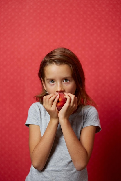 Foto a menina feliz do retrato come um pêssego em um fundo vermelho