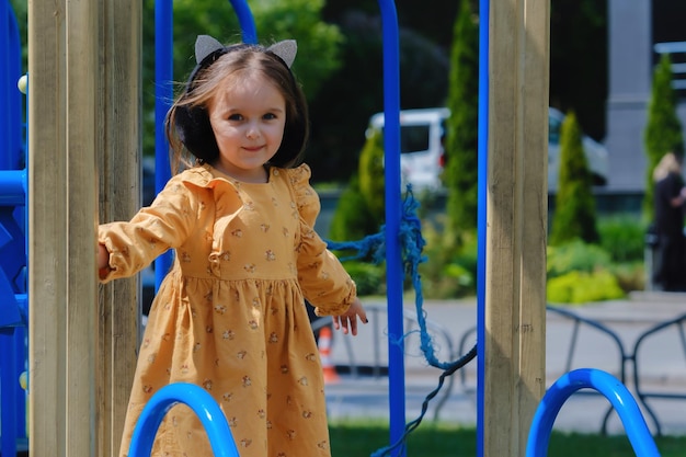 A menina feliz está jogando no campo de jogos no parque