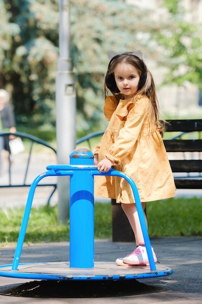 A menina feliz está jogando no campo de jogos no parque