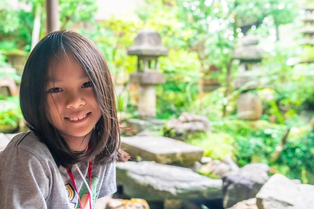 Foto a menina feliz está sentada no jardim japonês