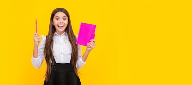 A menina feliz teve uma ideia segurando o livro e apontando a caneta para cima fundo amarelo eureka Banner de aluna Retrato de aluno de escola com espaço de cópia