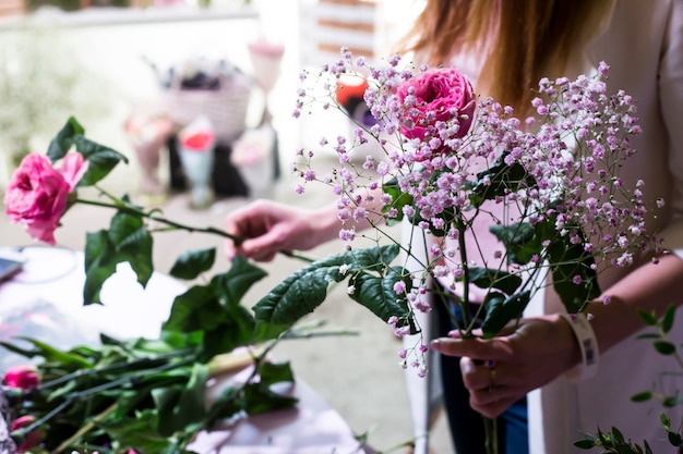 A menina florista cria um buquê suave de gypsophila e rosas