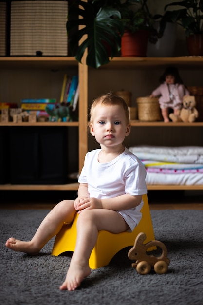 A menina fofa da criança, treinando penico, brincando com seus brinquedos no penico