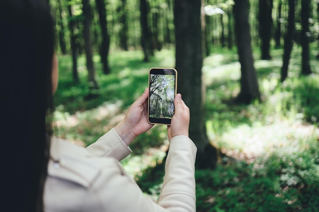 A menina fotografa a floresta Linda foto no telefone