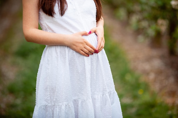 A menina grávida fez um coração com os dedos na barriga