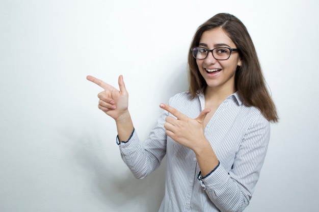 Foto a menina indiana feliz está no fundo branco com exibição do espaço da cópia.