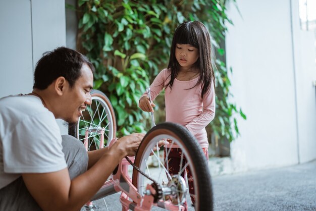 A menina instala um pedal com o pai