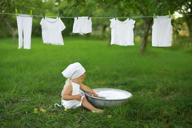 A menina lava a roupa branca na bacia no jardim na natureza