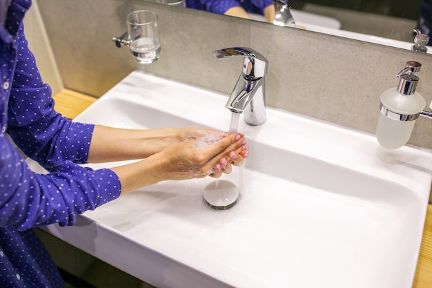 A menina lava as mãos com sabonete Uma gota de sabonete Lave as mãos durante uma pandemia Lavar as mãos Lavatório com sabonete Lavar as mãos com sabonete líquido Linda manicure com sabonete Limpe as mãos