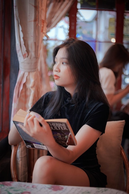 A menina lendo um livro e olhando pela janela