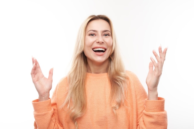 A menina loira positiva do retrato se alegra emocionalmente e se sente feliz e satisfeita isolada no banner de publicidade de fundo branco