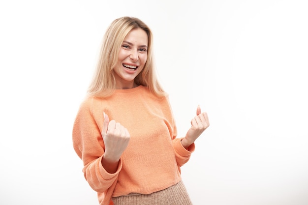 A menina loira positiva do retrato se alegra emocionalmente e se sente feliz e satisfeita isolada no banner de publicidade de fundo branco