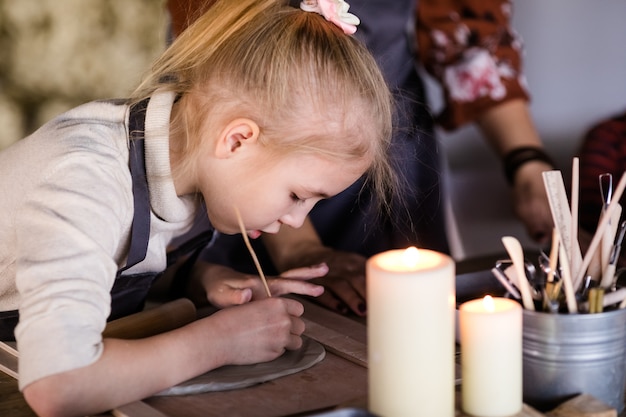 A menina loura esculpe da argila no estúdio. Aula de arte