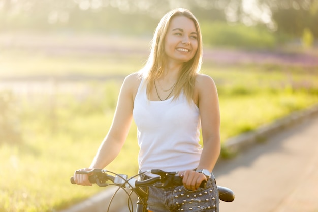 A menina loura que monta uma bicicleta