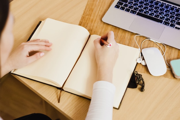 A menina mantém registros em seu diário, fazendo negócios e negócios, usando um computador e um notebook