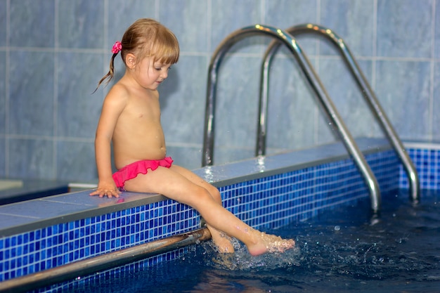 A menina molha as pernas na piscina